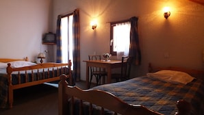 A room with two wooden beds, a small table with chairs, and a television on a shelf. - Hotel du Doron (Beaufort)