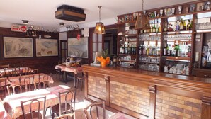 A bar area with wooden furniture, a brick counter, and shelves with bottles and glasses. - Hotel du Doron (Beaufort)
