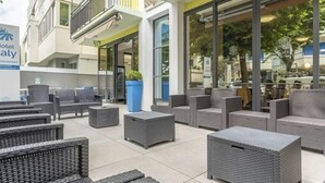 An outdoor seating area with wicker furniture and a blue planter. - Hotel Italy (Misano Adriatico)