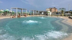 A large outdoor swimming pool with clear water, surrounded by a deck with lounge chairs and umbrellas. - Hotel Italy (Misano Adriatico)
