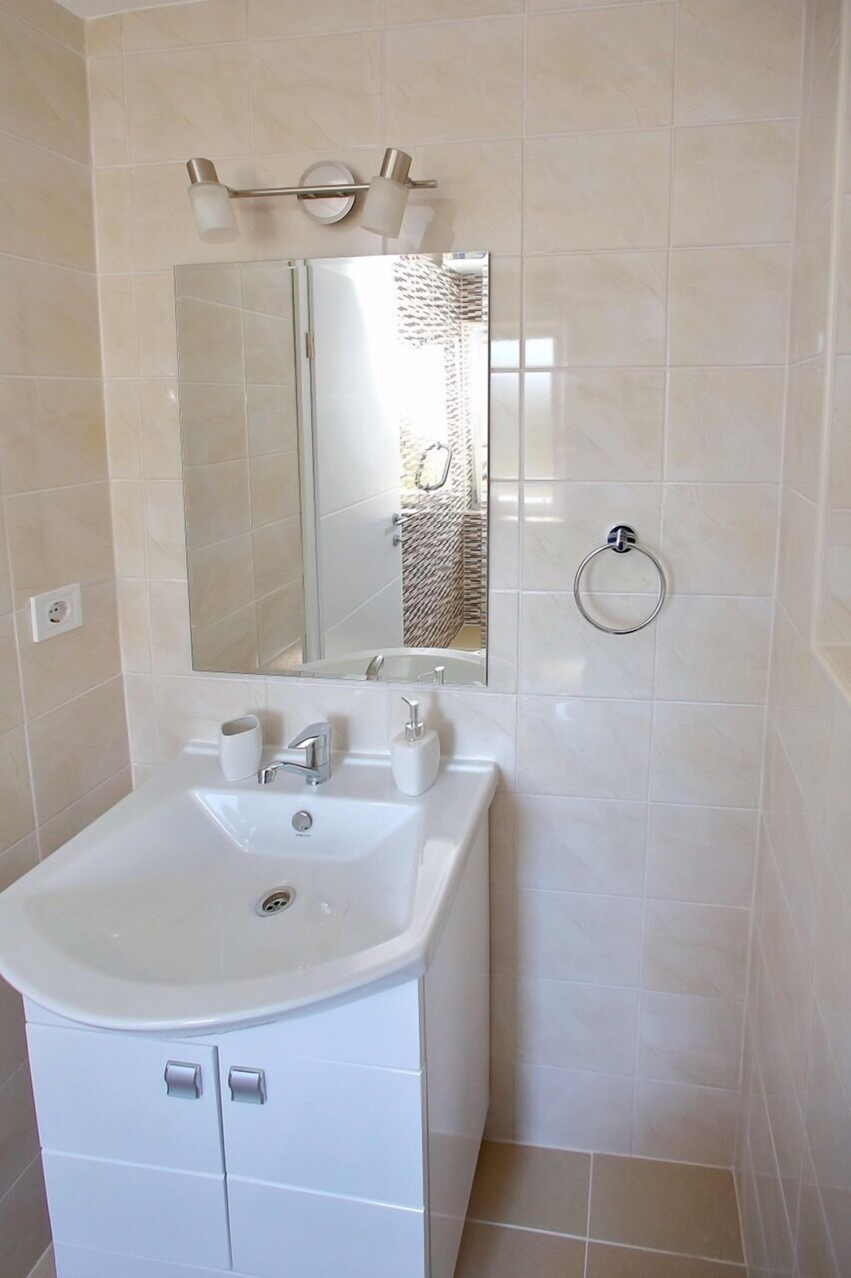 Une salle de bain avec un lavabo blanc, un miroir et un porte-serviettes fixé au mur.