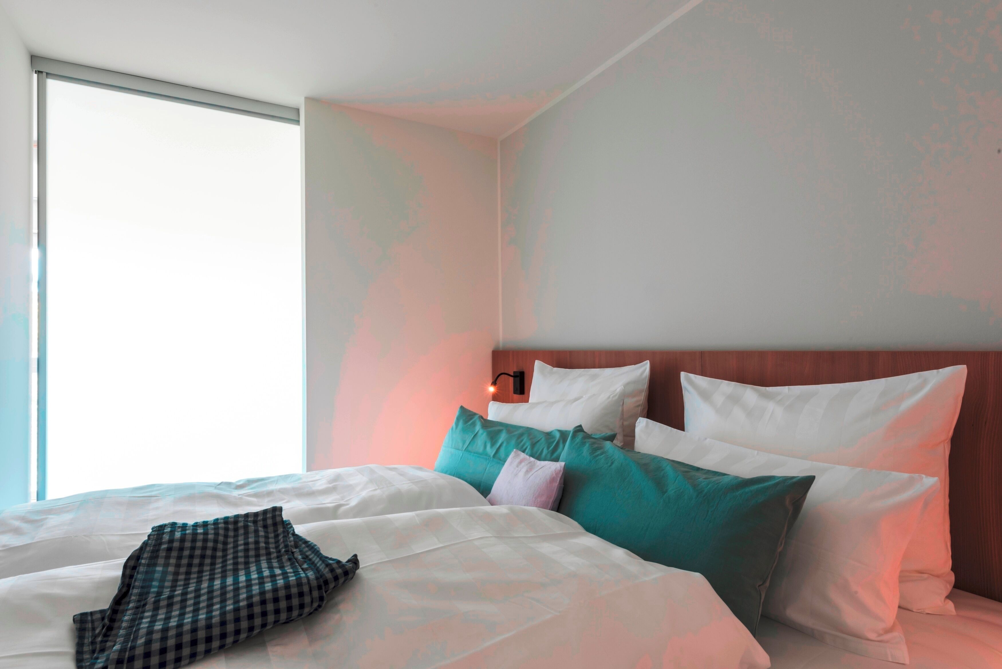 Ein Hotelzimmer mit einem großen Bett, mehreren Kissen, einem Nachttisch und einem Fenster.