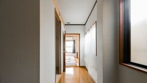 Un pasillo estrecho con suelo de madera y paredes blancas.