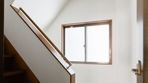Una escalera conduce a una habitación con ventana, suelo de madera y una puerta.