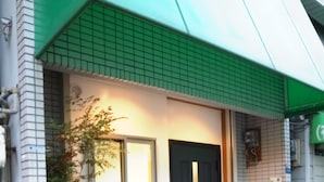 Un edificio con toldo verde, puerta negra y ventana.