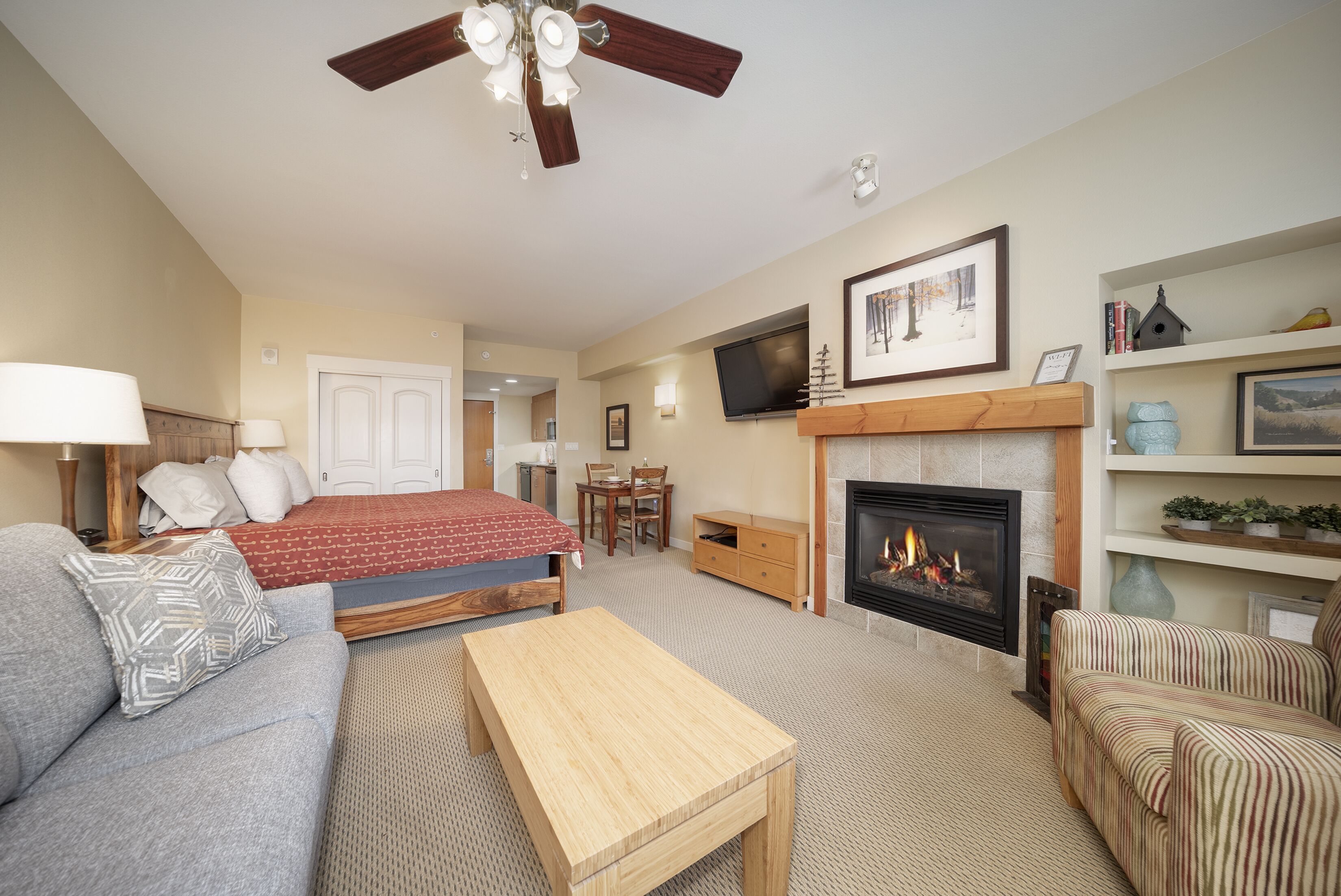 A cozy living room with a fireplace, a sofa, a coffee table, and a TV.