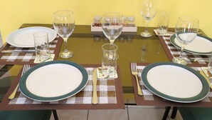 A dining table set with plates, cutlery, and glasses, with a bottle of water and condiment jars on the table. - Island Away – 2 Bedroom Nestled in Angel Estate, Near Kingston & Ocho Rios (Angels Estate)