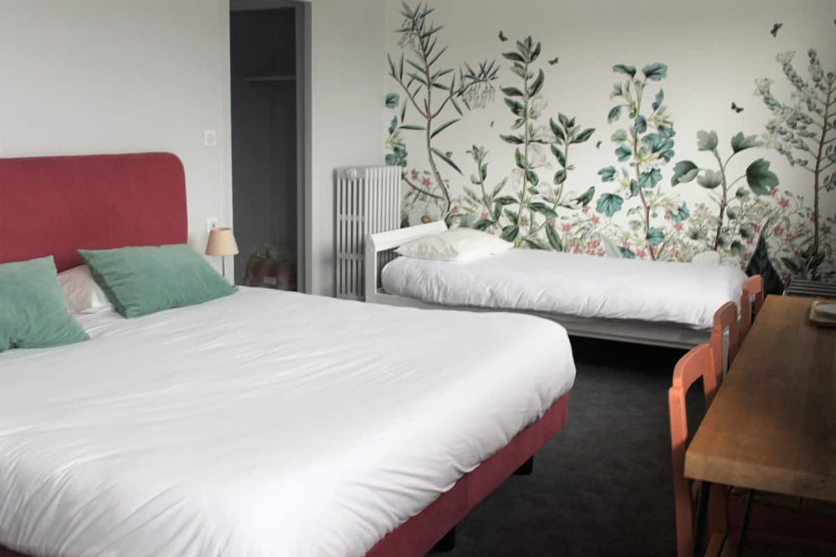 A room with two beds, a wooden table, and a radiator.