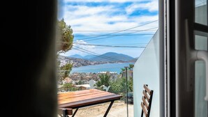 An open door with a view of a balcony, a wooden table, and a chair.