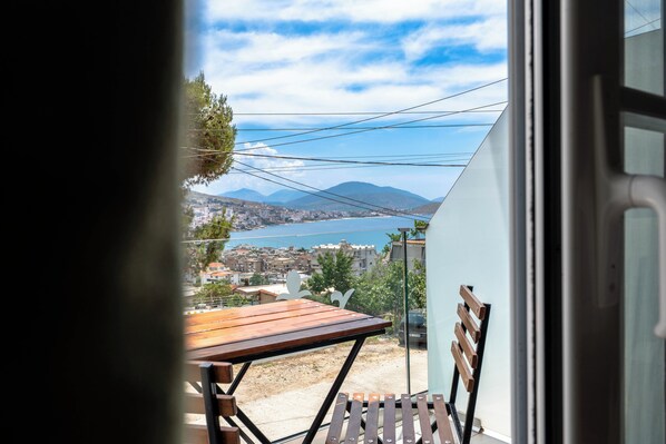 An open door with a view of a balcony, a wooden table, and a chair.