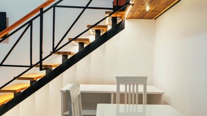 A modern interior with a staircase, a white table, and a chair.