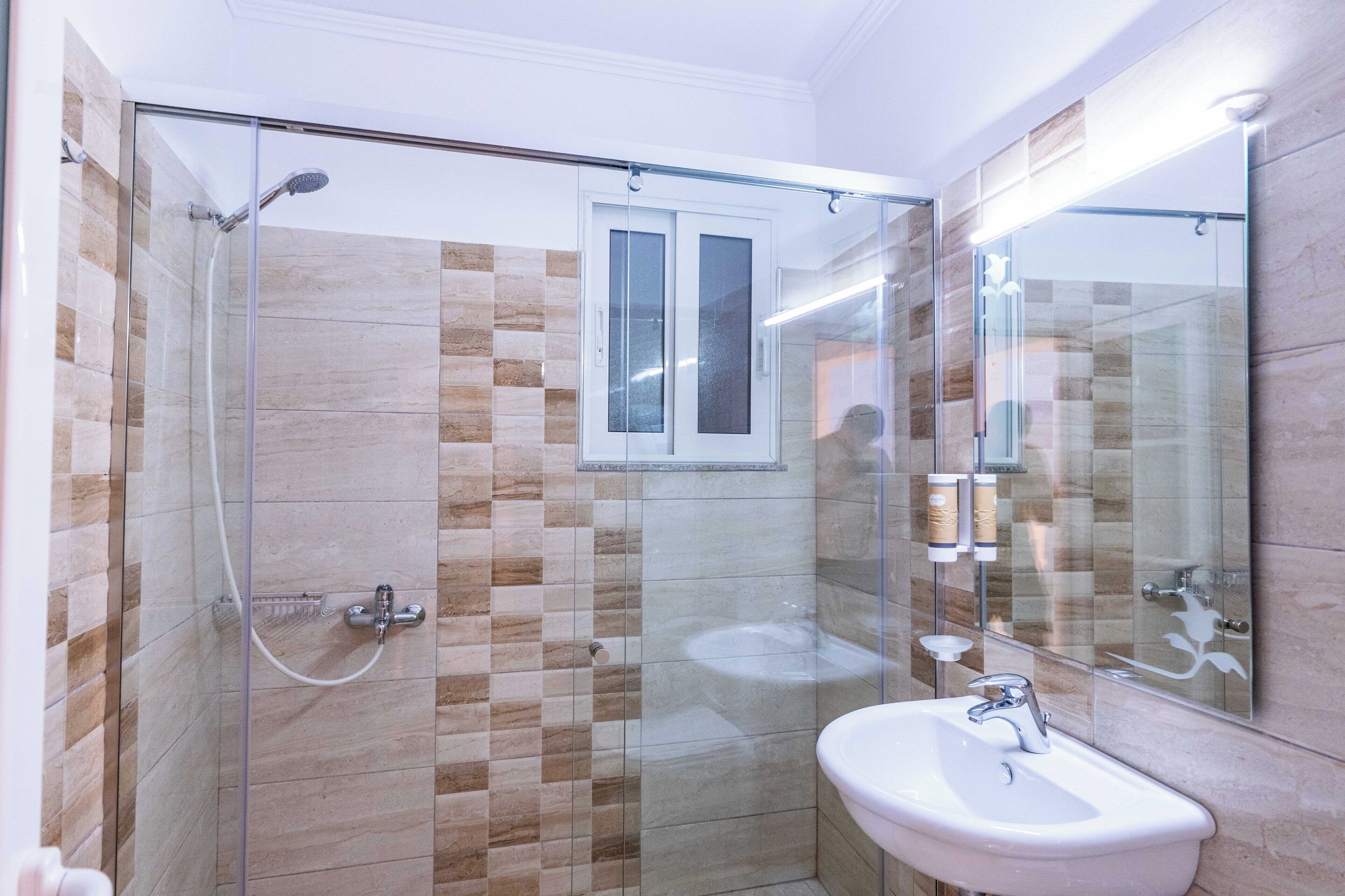 Un bagno moderno con cabina doccia in vetro, lavandino e specchio.