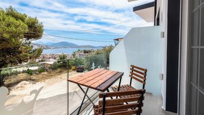 A balcony with a wooden table and chairs, overlooking a coastal town and mountains. - Crown Deluxe Apartments (Sarande)