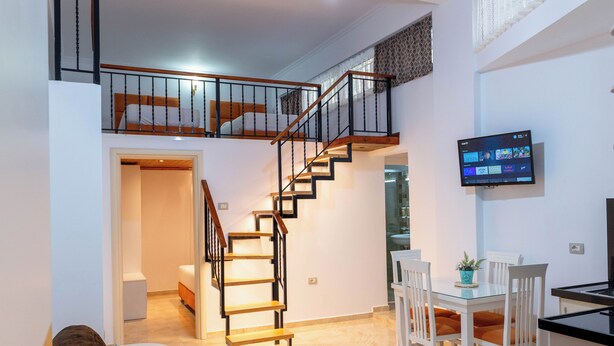 A modern interior with a staircase, a dining area, and a TV mounted on the wall.