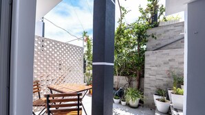 A patio with a wooden table and chairs, potted plants, and a lattice fence.
