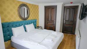 A neatly made bed with white linens, a teal upholstered headboard, and a round mirror above it. - My Way Teras Butik Otel (Adalar)