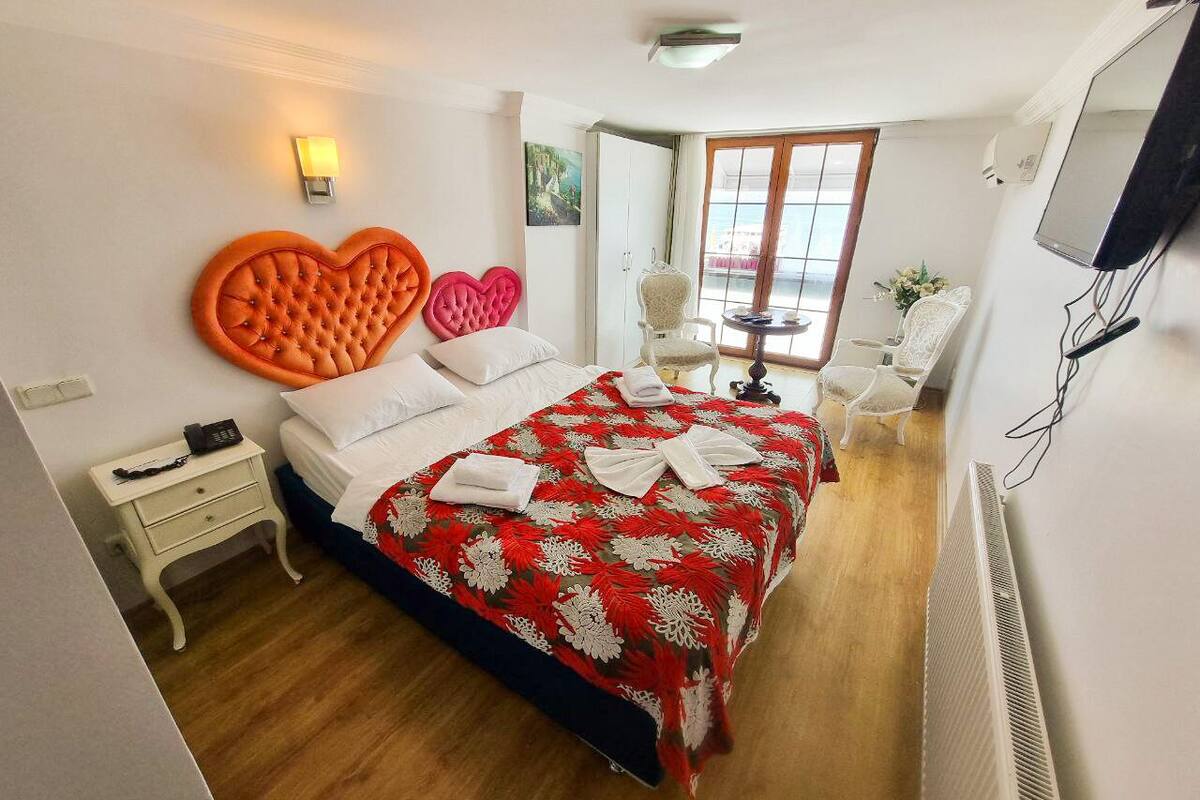 A hotel room with a bed, a nightstand, a window, and a TV.