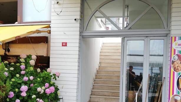 A covered outdoor area with a staircase leading to a building entrance, surrounded by potted plants and a table. - My Way Teras Butik Otel (Adalar)