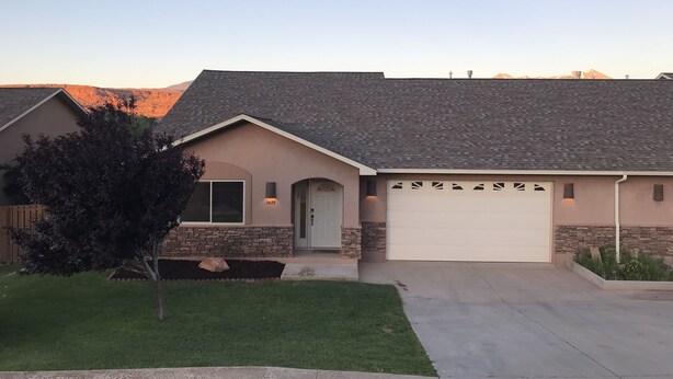 A single-story house with a stone facade, a garage, and a well-maintained lawn.
