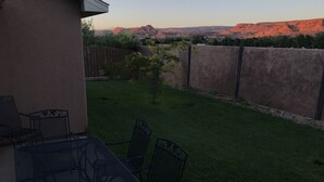 A patio with a table and chairs, a small tree, and a view of red rock formations.