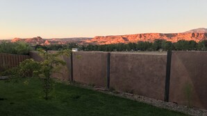 A fenced yard with a small tree and a view of a mountain range in the background.