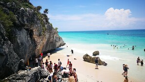 Una playa con acantilados rocosos y agua turquesa cristalina.