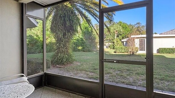 Une pièce dotée d’une porte-fenêtre coulissante donnant sur un jardin avec un palmier et une pelouse.