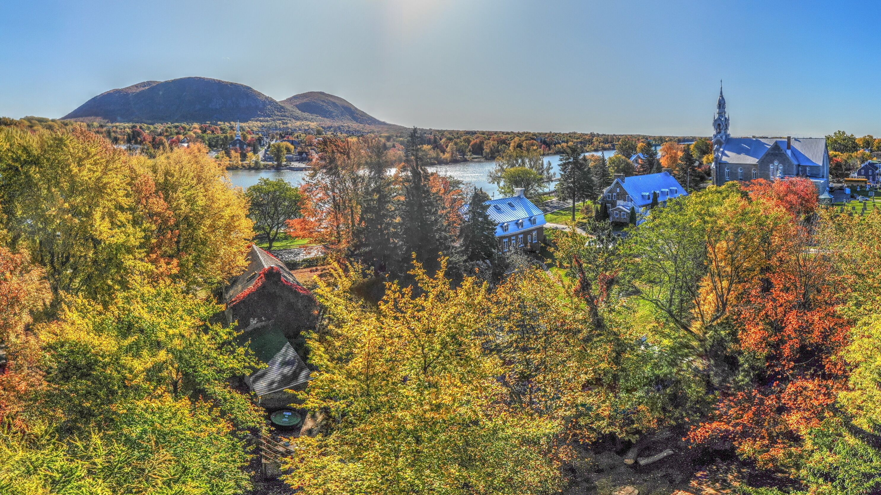 Ein malerischer Blick auf eine Stadt mit Herbstlaub, einen Fluss und einen Berg im Hintergrund.