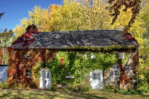 Une maison en pierre aux murs recouverts de lierre et dotée d’un toit en pente.