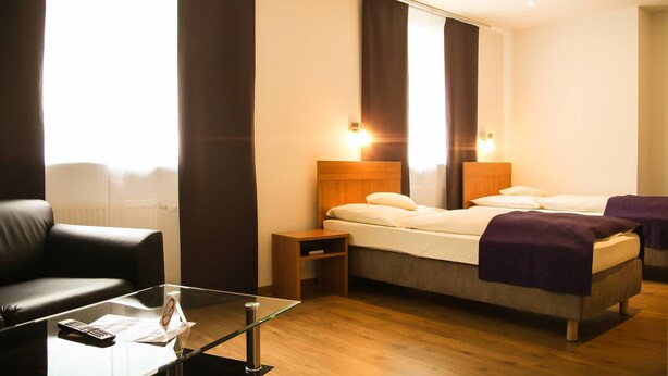 Quarto de hotel com uma cama, uma mesa de centro de vidro, um controle remoto e uma mesa de cabeceira.