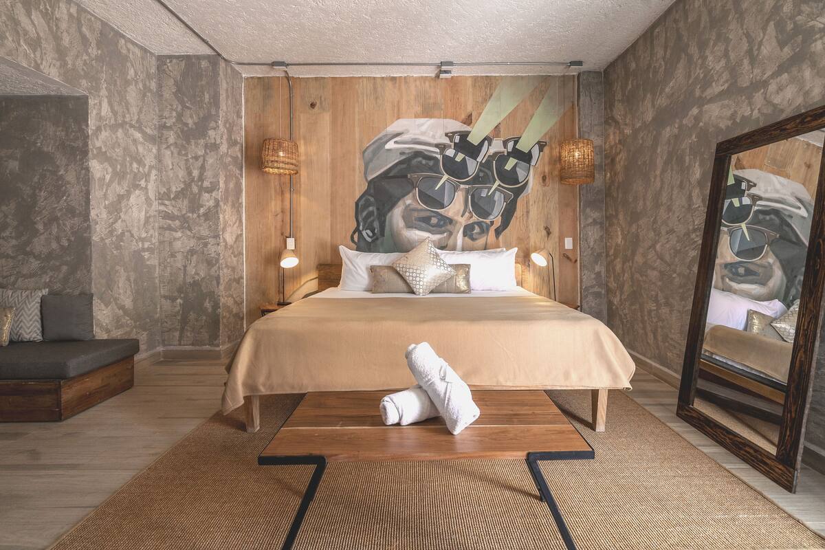 Een moderne slaapkamer met een groot bed, een houten hoofdbord en een unieke wanddecoratie.