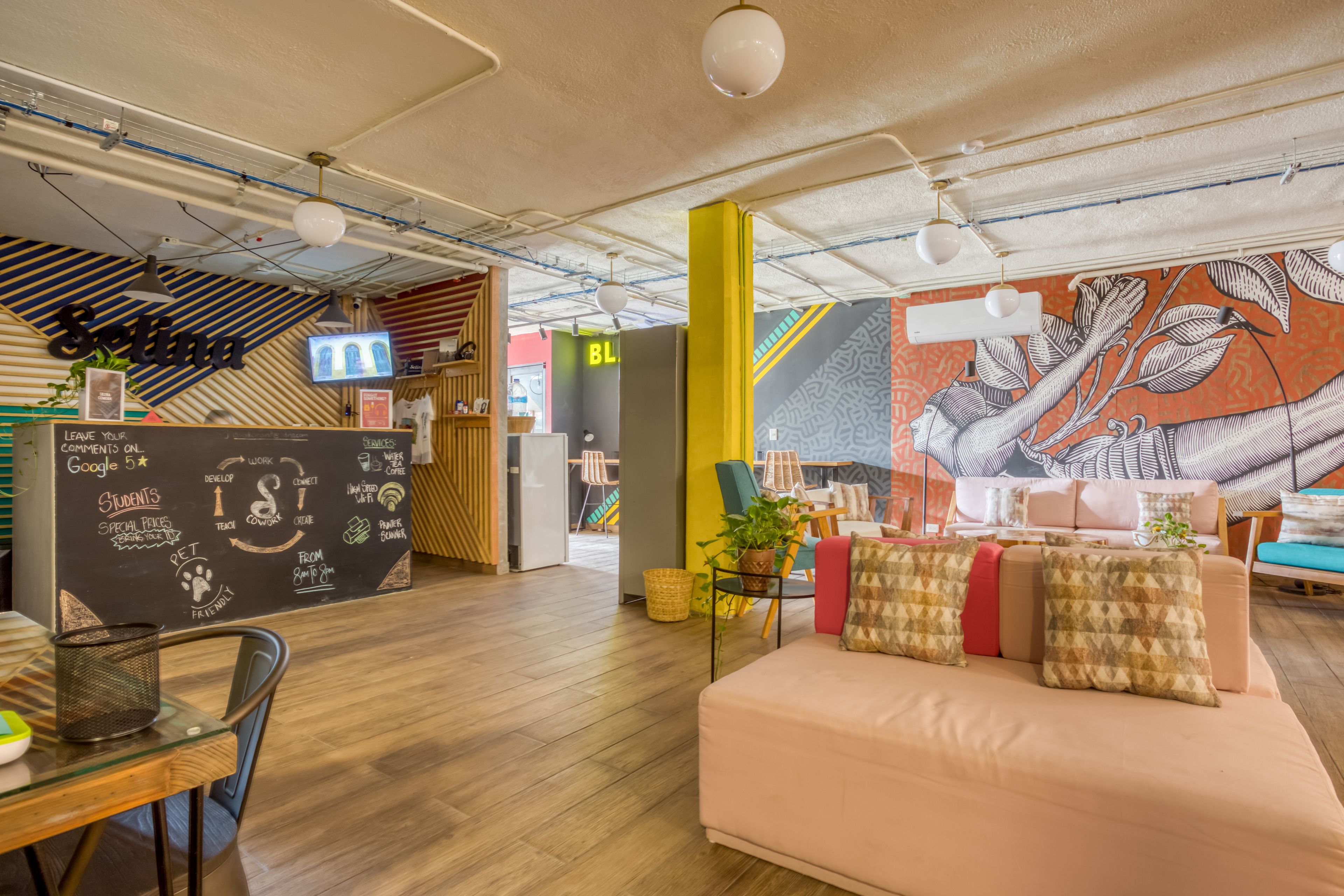 A modern workspace with a chalkboard wall, wooden furniture, and a mural.