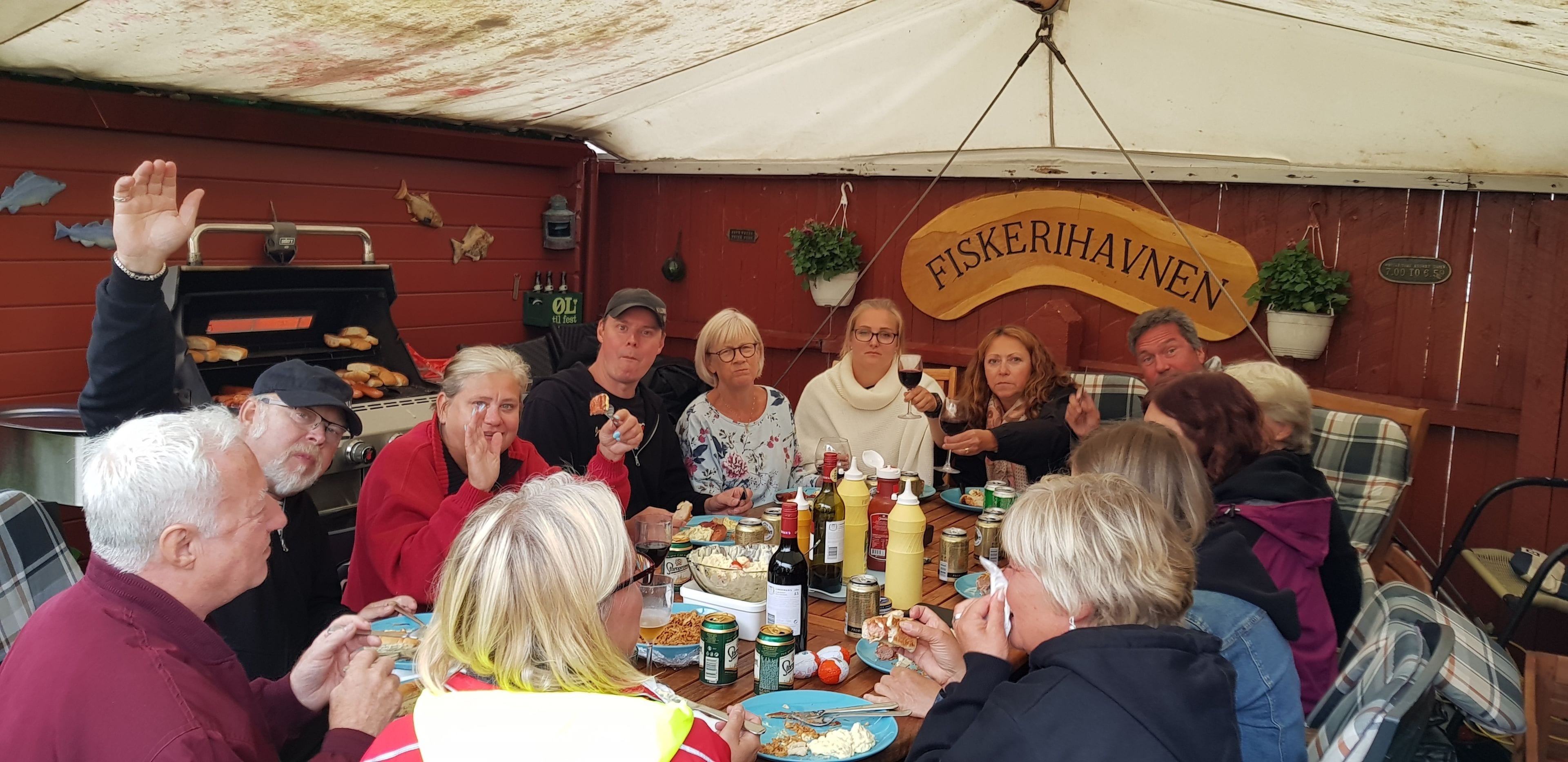 Un grupo de personas cenando en una mesa de madera con diferentes platos y bebidas.