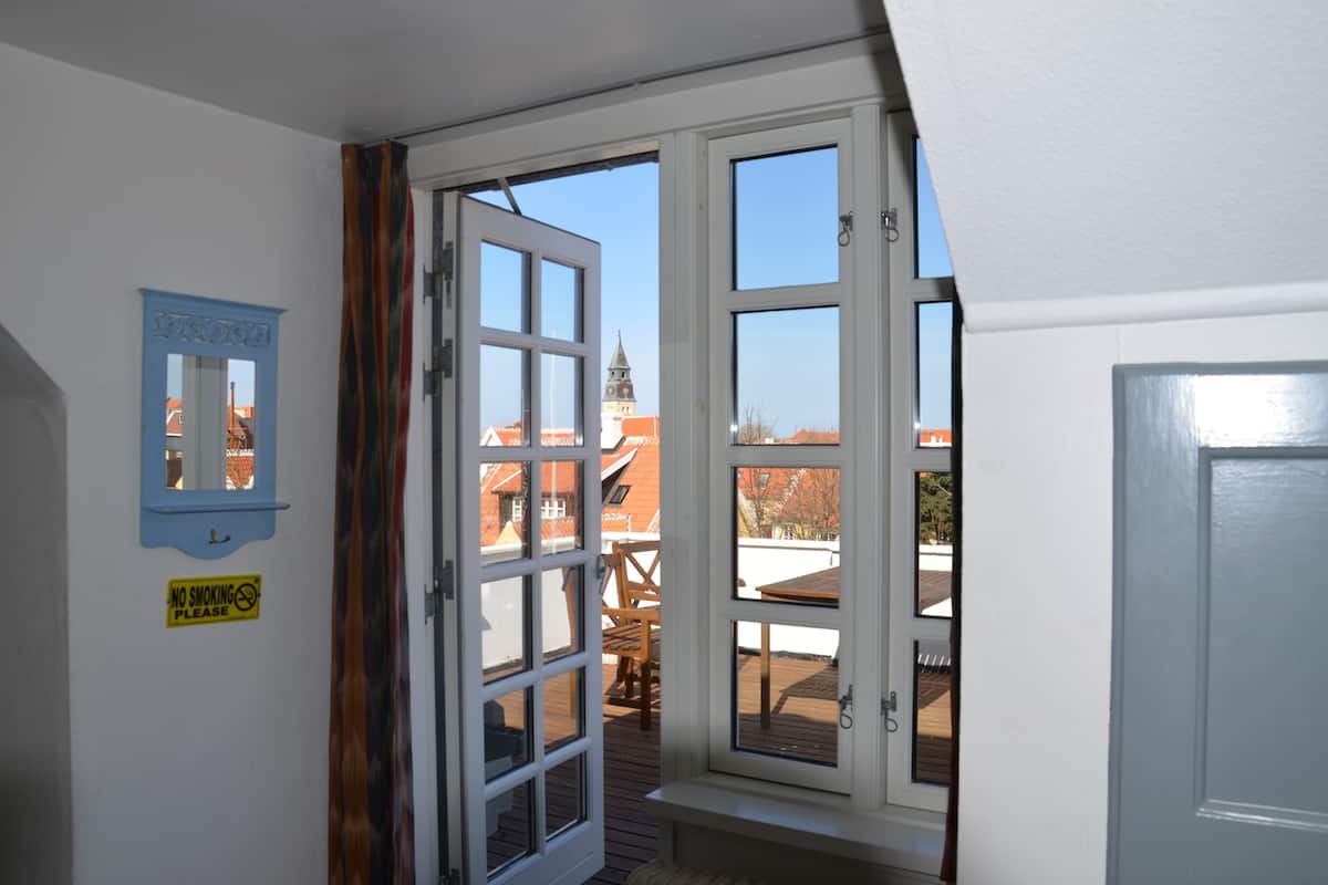 A room with a large window, a blue mirror, and a 'No Smoking' sign.