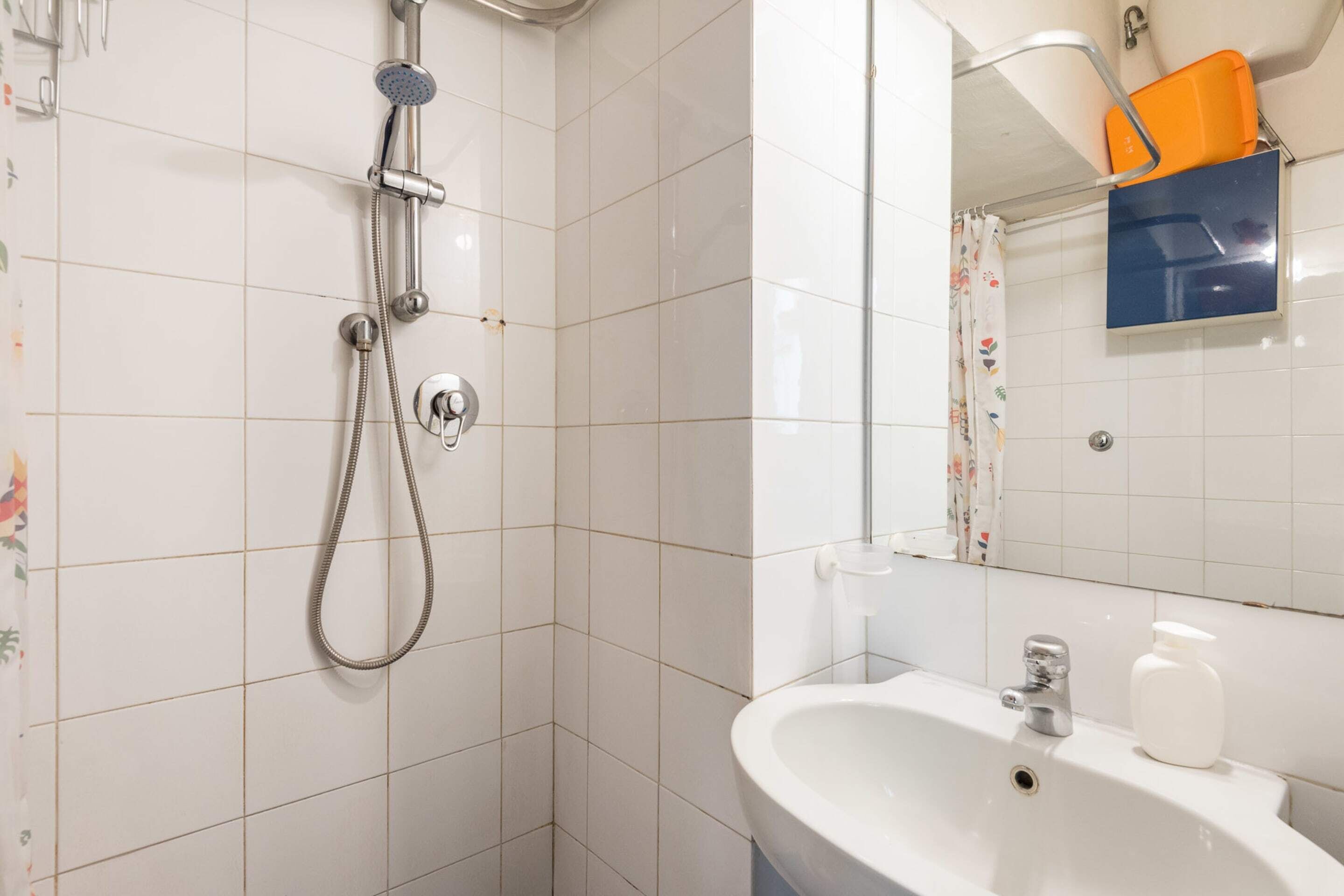 A bathroom with a shower, sink, and mirror.