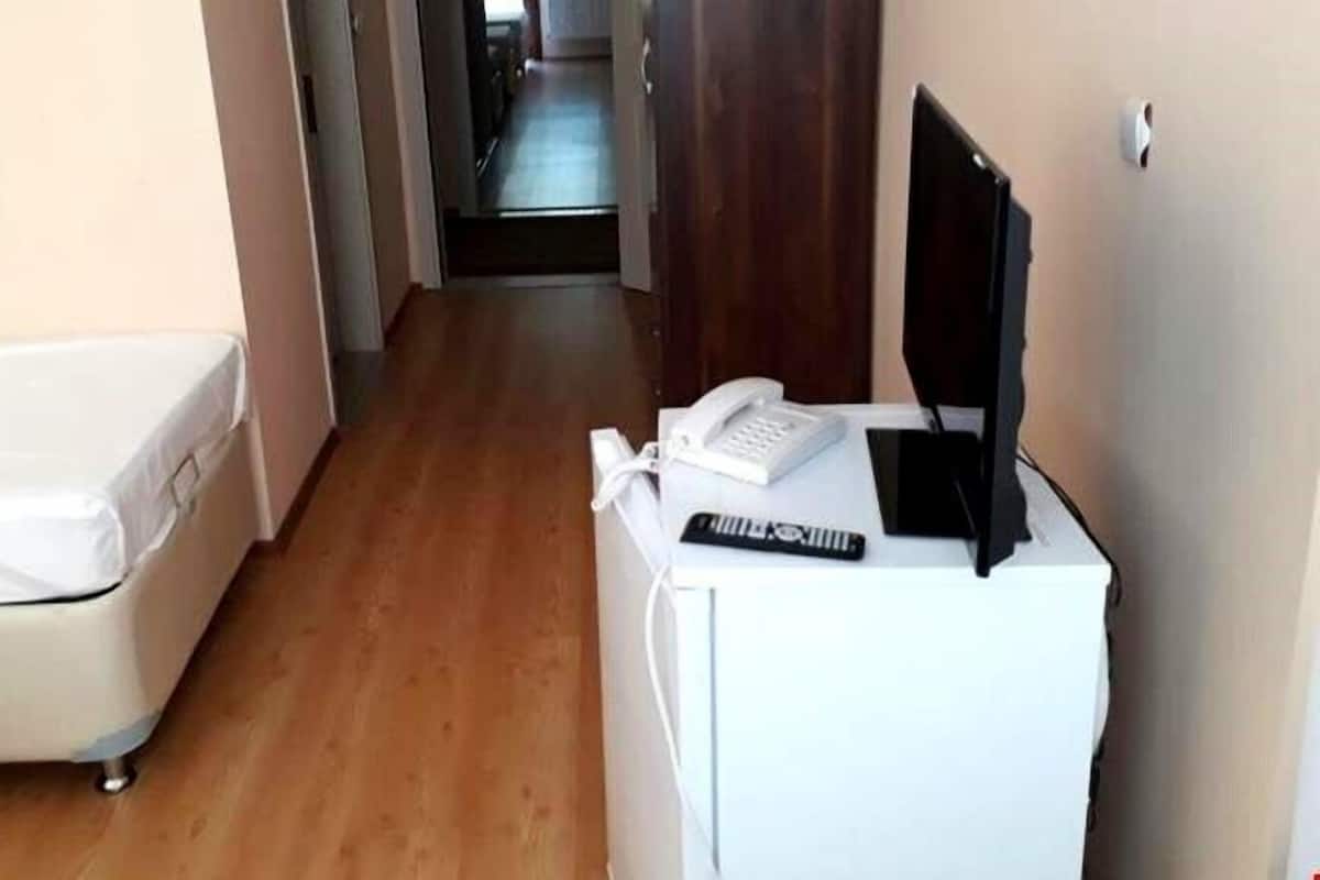 Habitación de hotel con cama, escritorio, teléfono, control remoto y televisión.