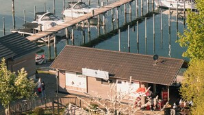 Un port de plaisance avec des bateaux amarrés, une jetée en bois et un bâtiment portant une enseigne.