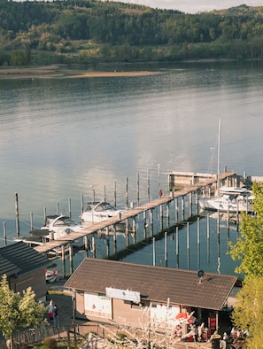 A marina with boats docked, a wooden pier, and a building with a sign. - Seehotel Villa Linde (Bodman-Ludwigshafen)