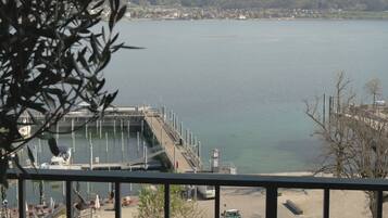 Vista de un lago con un muelle, un paseo peatonal y un pueblo a lo lejos.