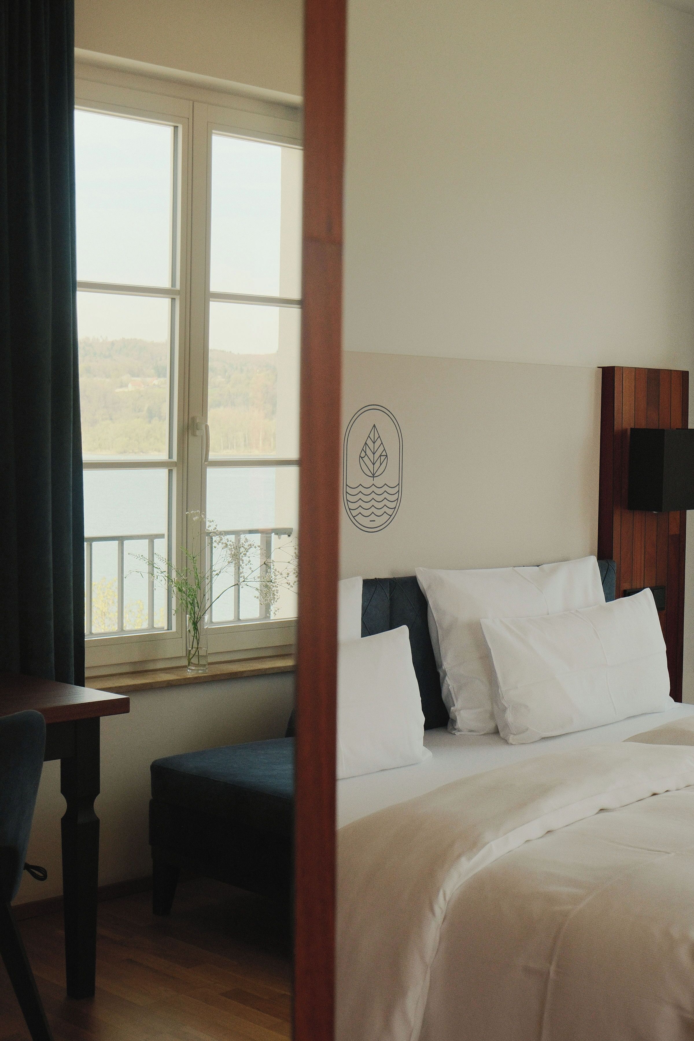 A hotel room with a bed, a desk, a chair, a window with a view, and a wall-mounted television.