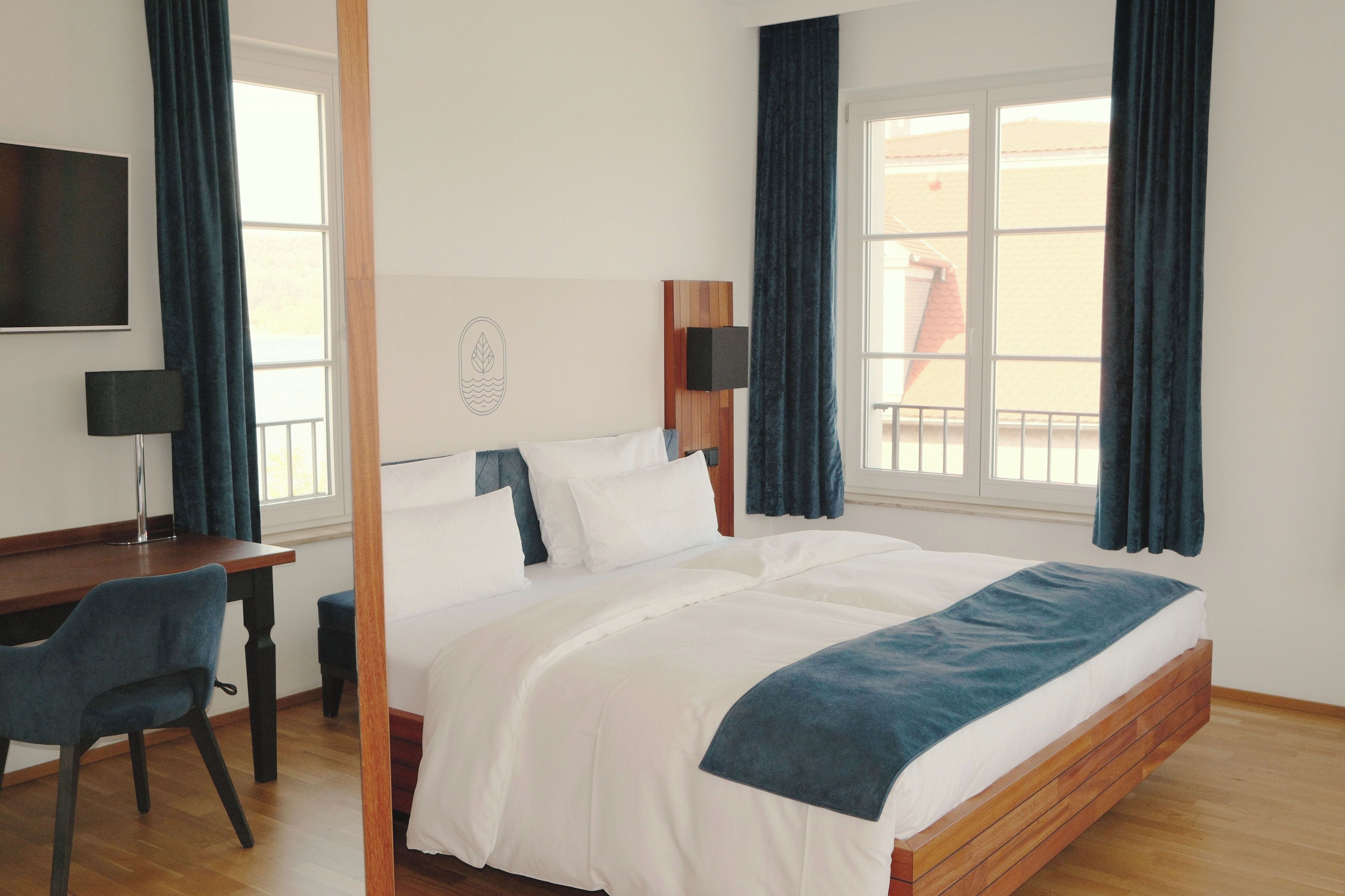 Une chambre d’hôtel équipée d’un lit, d’un bureau, d’une chaise, d’une télévision et d’une fenêtre avec des rideaux.