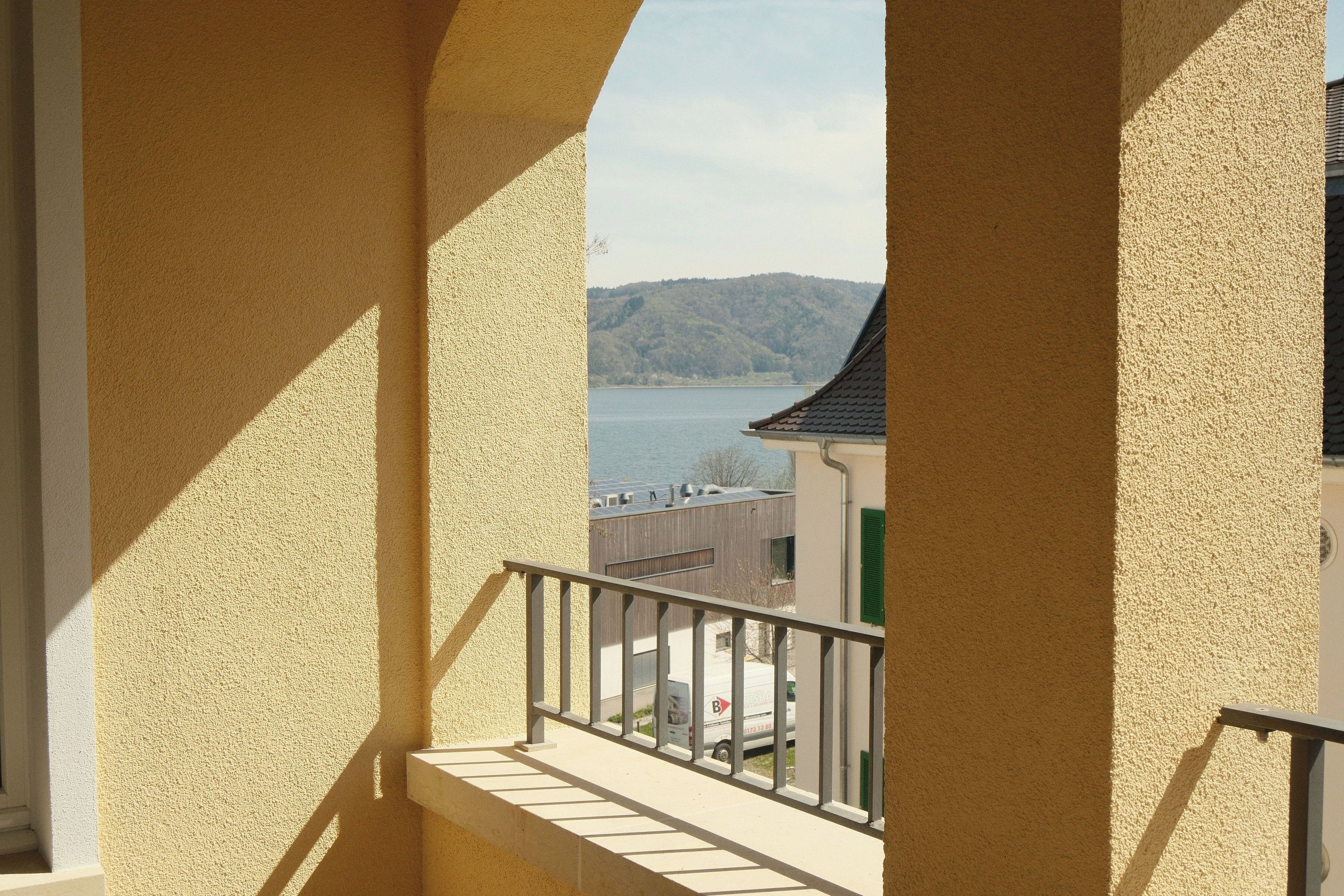 Ein Balkon mit Blick auf einen See und ein Gebäude am gegenüberliegenden Ufer.