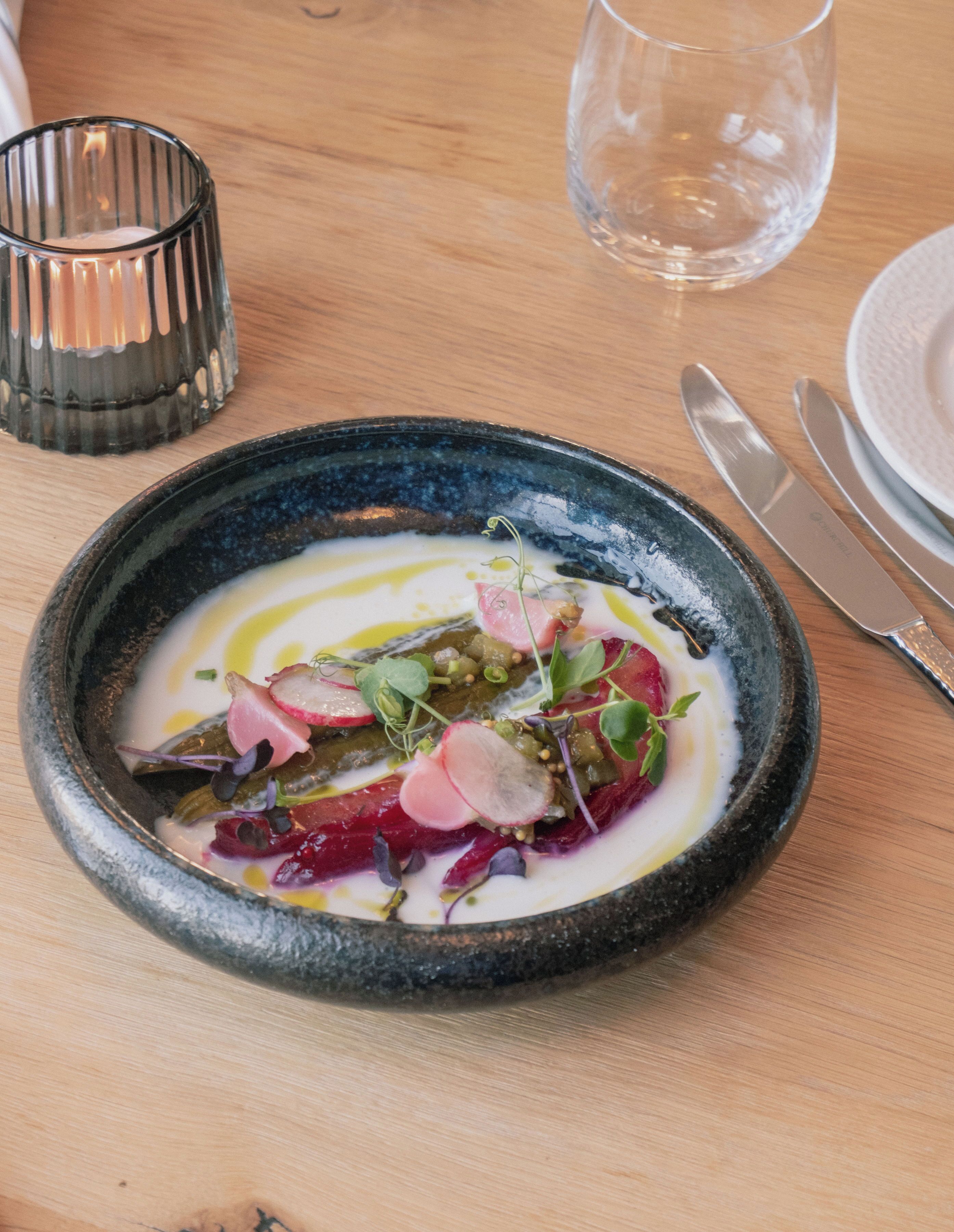 A plate of food with a variety of vegetables and a clear glass of water on a wooden table.
