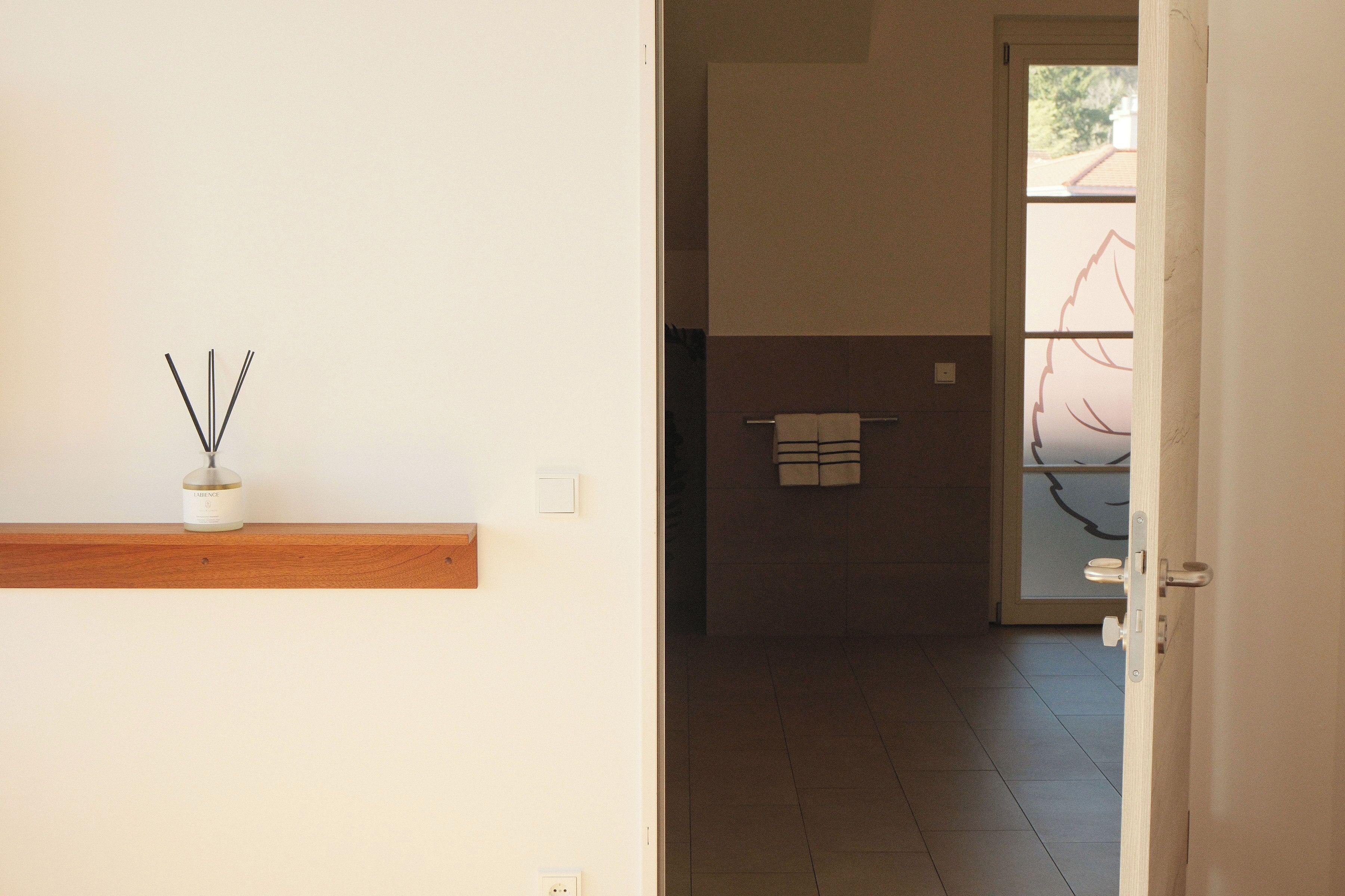 A hallway with a wooden shelf, a door, and a tiled floor.