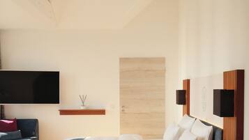 A modern bedroom with a bed, a TV, a small shelf, and a wooden headboard.