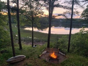 A lakeside campsite with a fire pit, benches, and a canoe. - Waterfront Paradise!!  2020 discount pricing for this 5 star luxury Home. (Bourne)