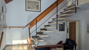 A staircase with a wooden handrail and metal balusters, leading to a landing with a desk and chair. - Charming 70s house with large garden (Heide)