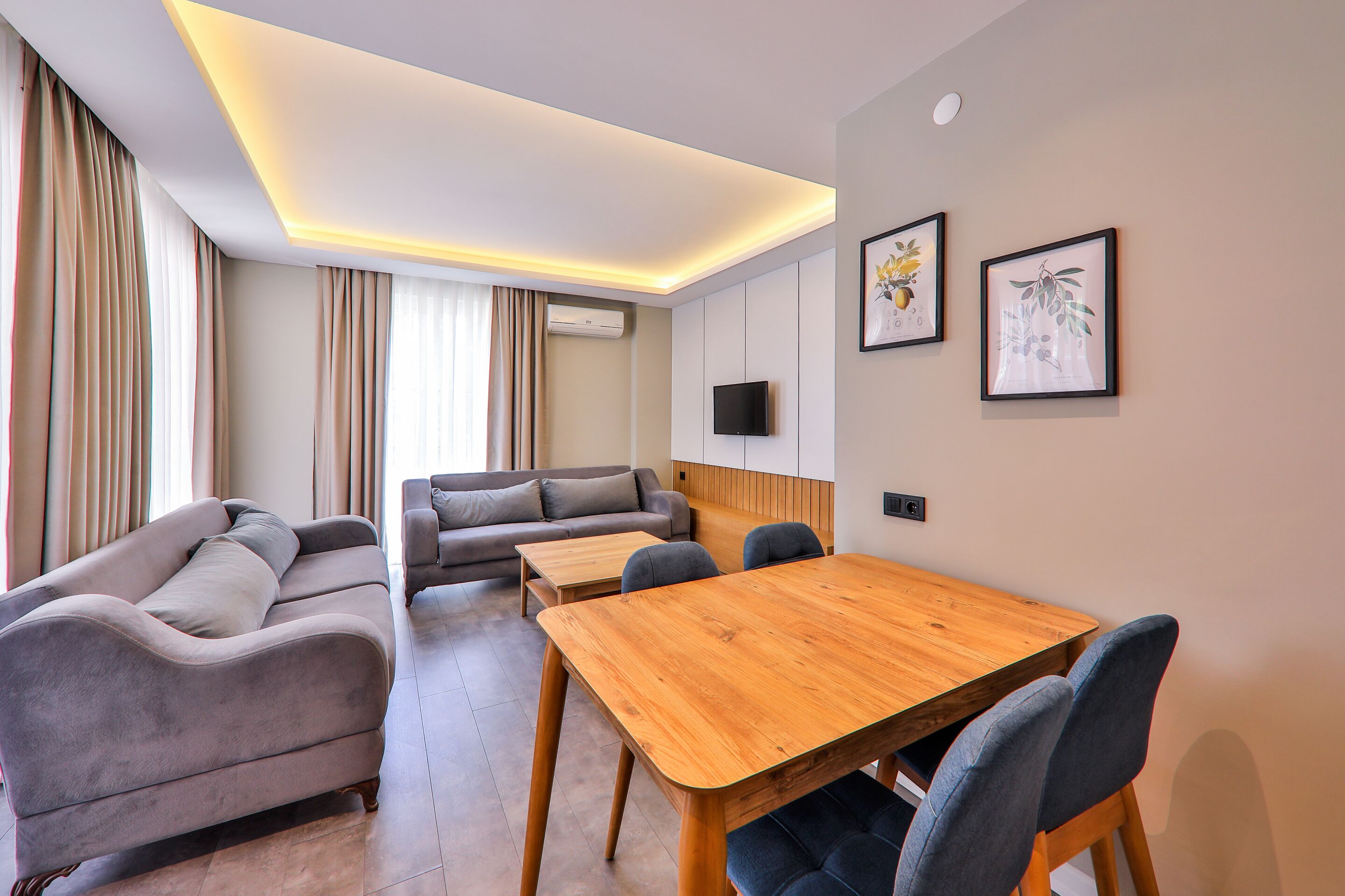 Un salon moderne avec un canapé, une table à manger en bois et un téléviseur fixé au mur.