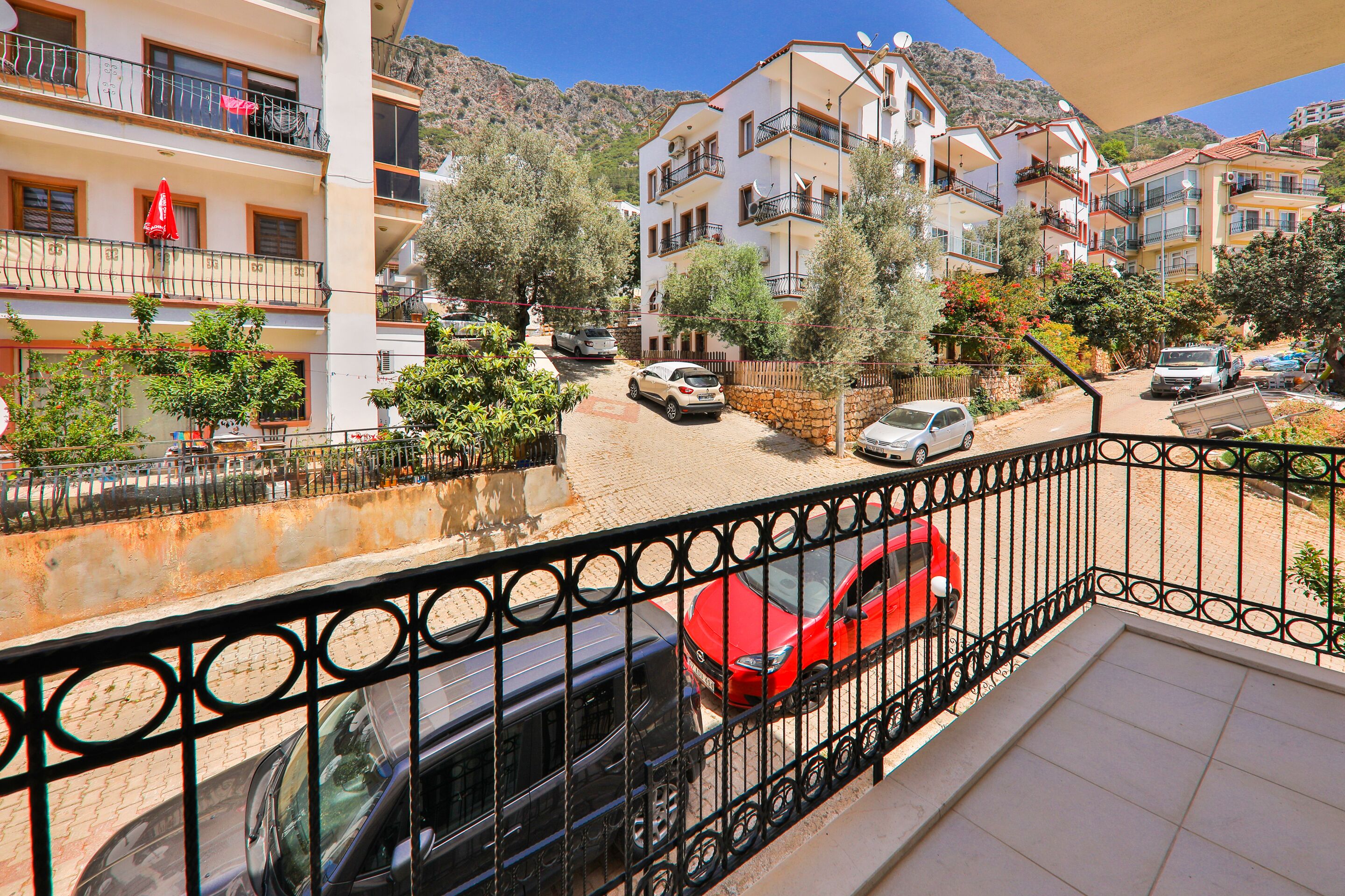 A residential area with multi-story buildings, balconies, and parked cars.