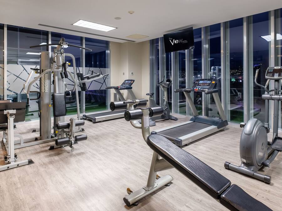 Een moderne sportschool met diverse fitnessapparaten, grote ramen en uitzicht over de stad.
